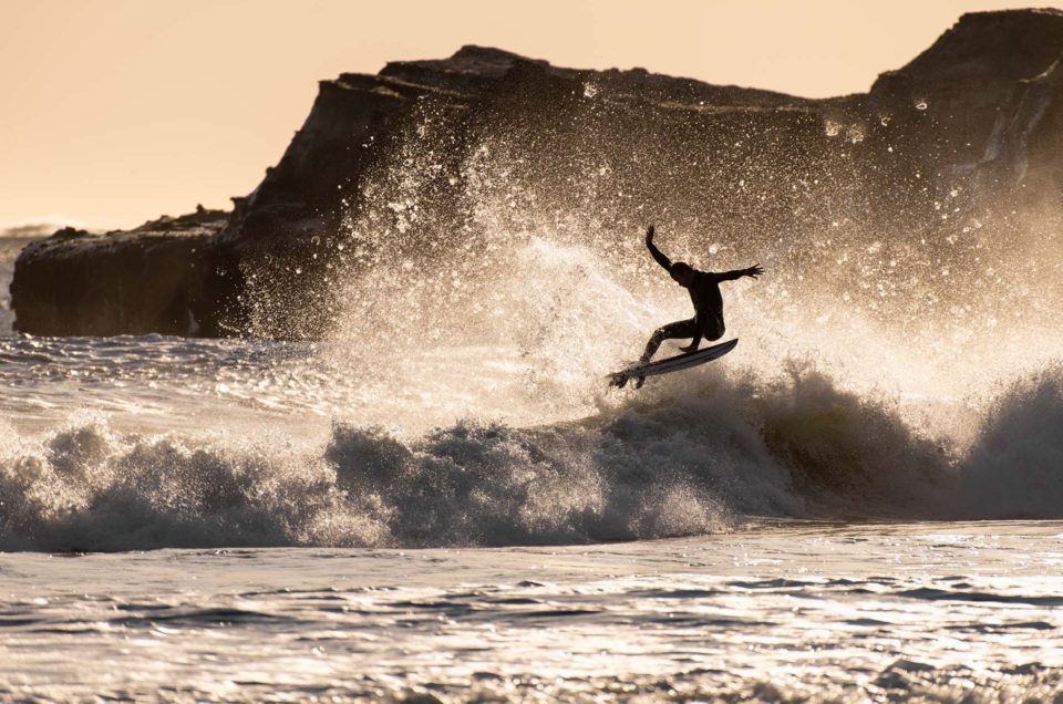 Surfer at Año Nuevo Reserve Flying off Wave with arms extended